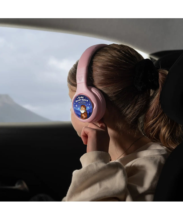 A child wearing ONANOFF pink Disney StoryPhones with Kids Audio Bible Old Testament StoryShield, listening to stories about Abraham and Issac. The girl looks out a car window at a distant mountain.